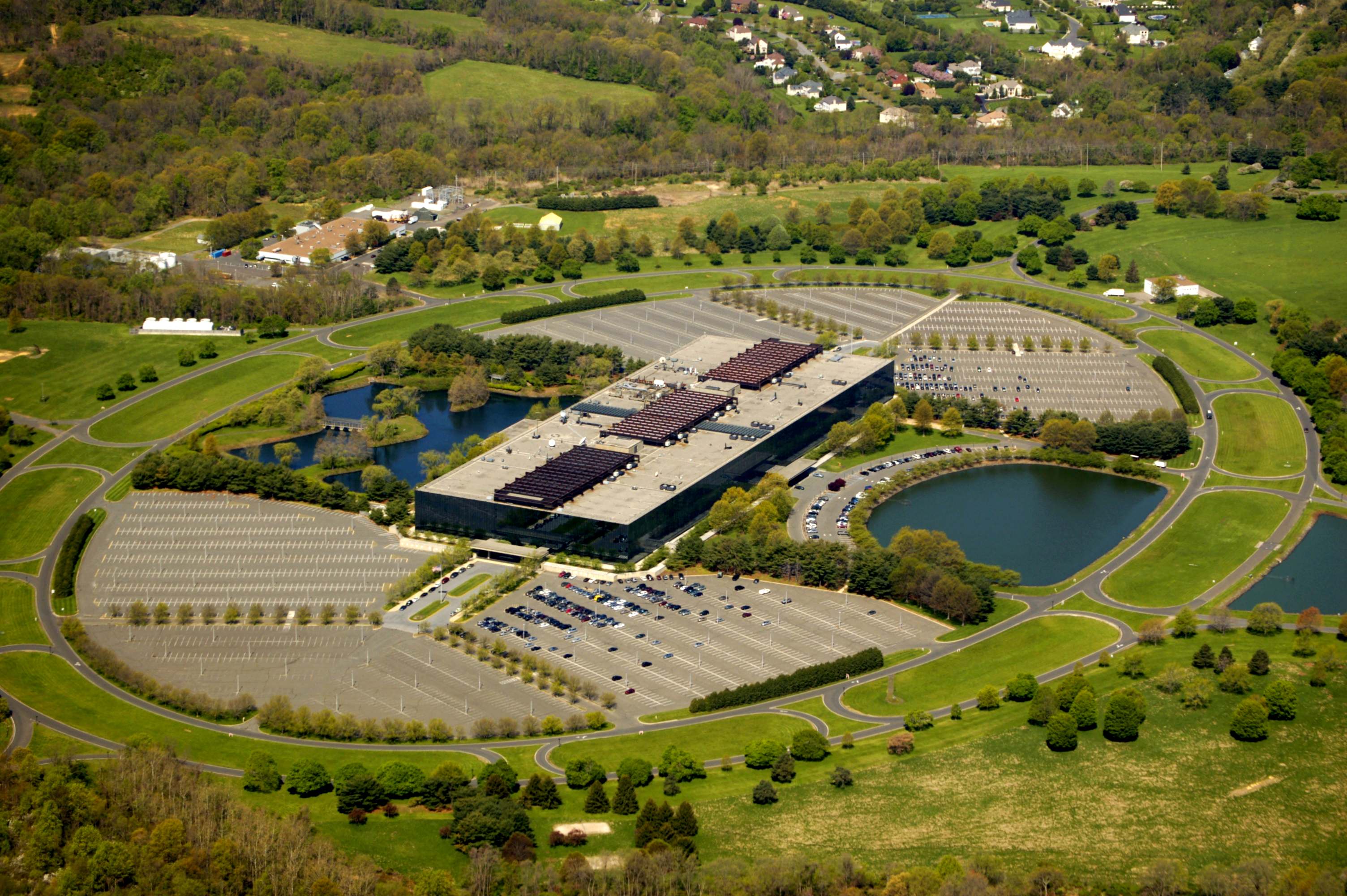Aerial view of the long, low Bell Works building on its landscaped grounds, with ponds and parking ovals.