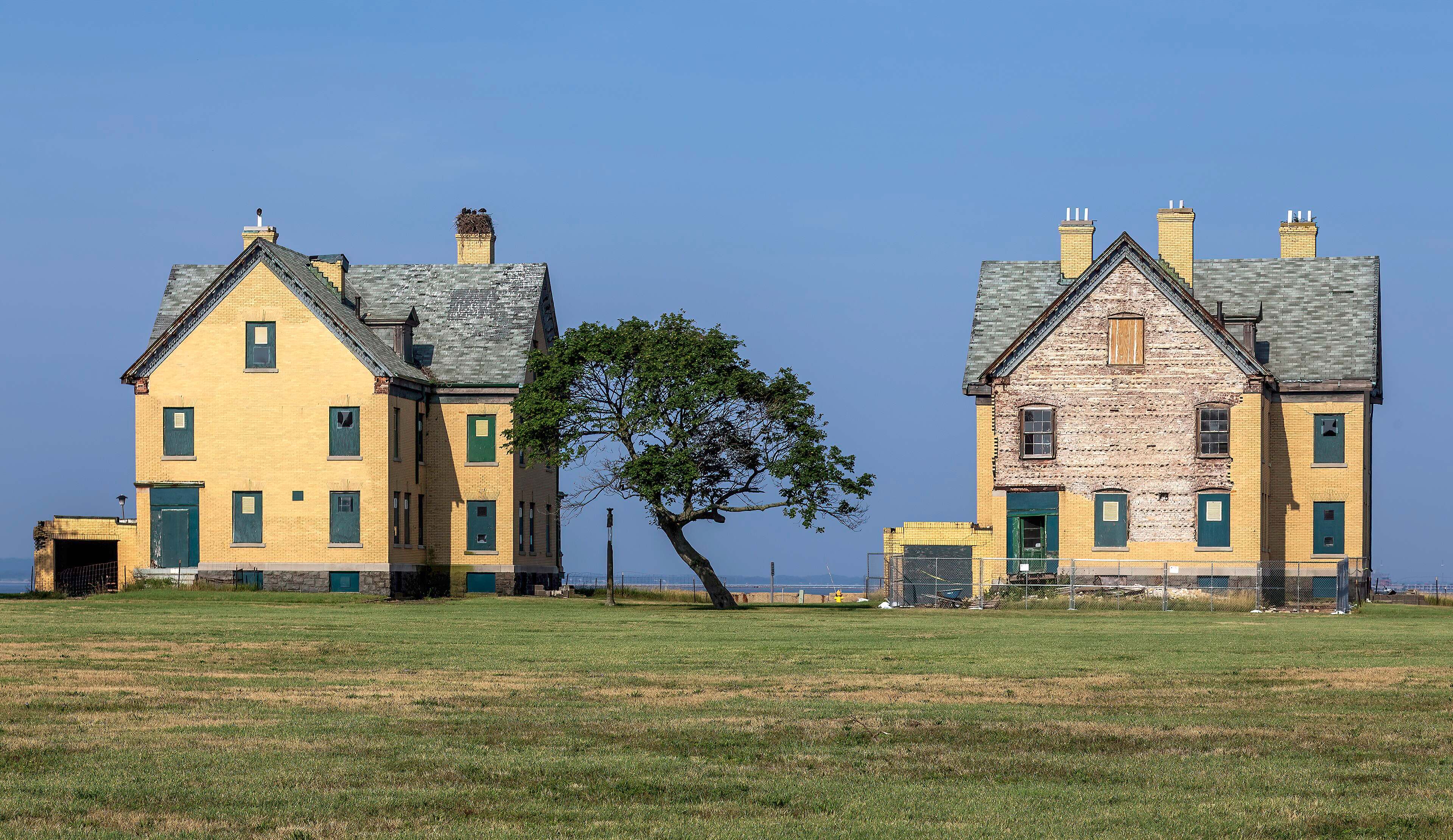 Two yellow officers' houses at Fort Hancock on Sandy Hook with a windswept tree between them.