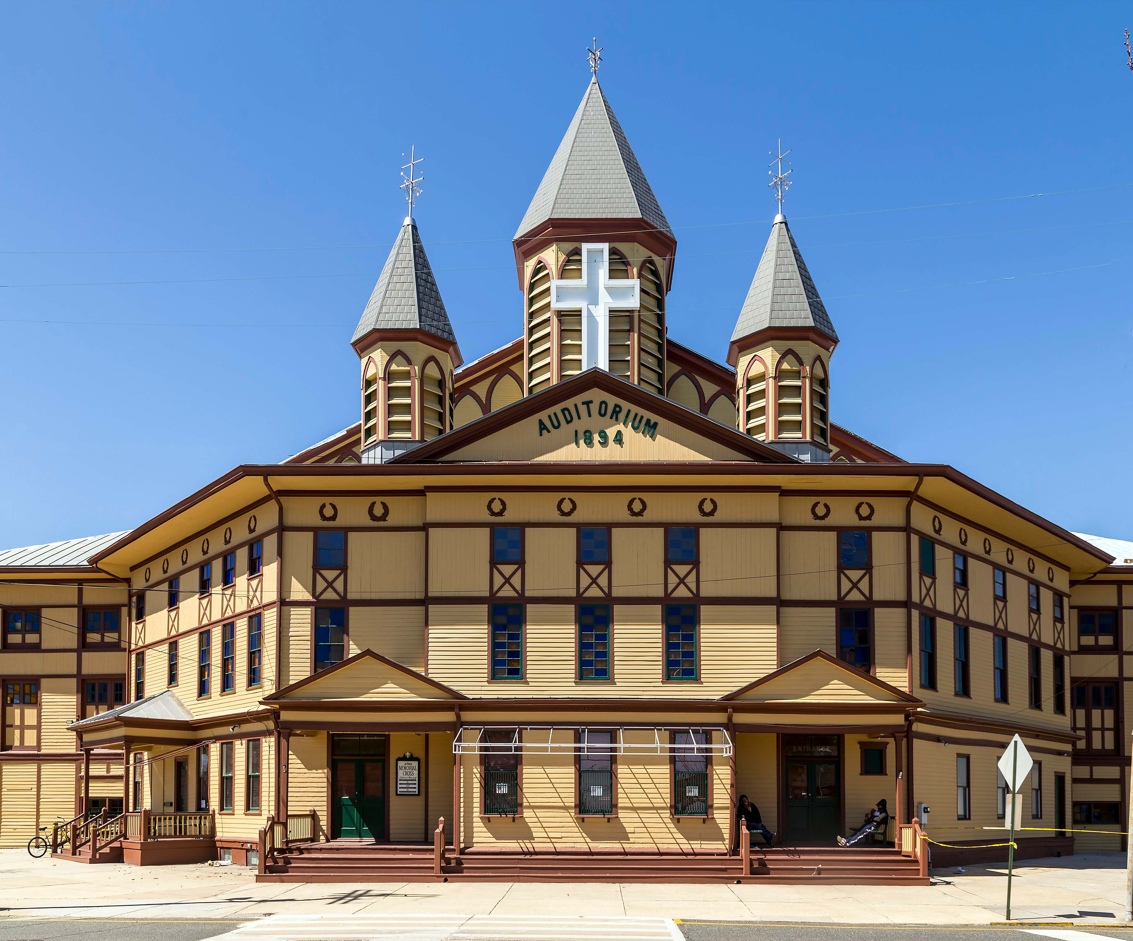 The Great Auditorium in Ocean Grove, a yellow timber building with three spires, a cross and the date 1894 on the gable.