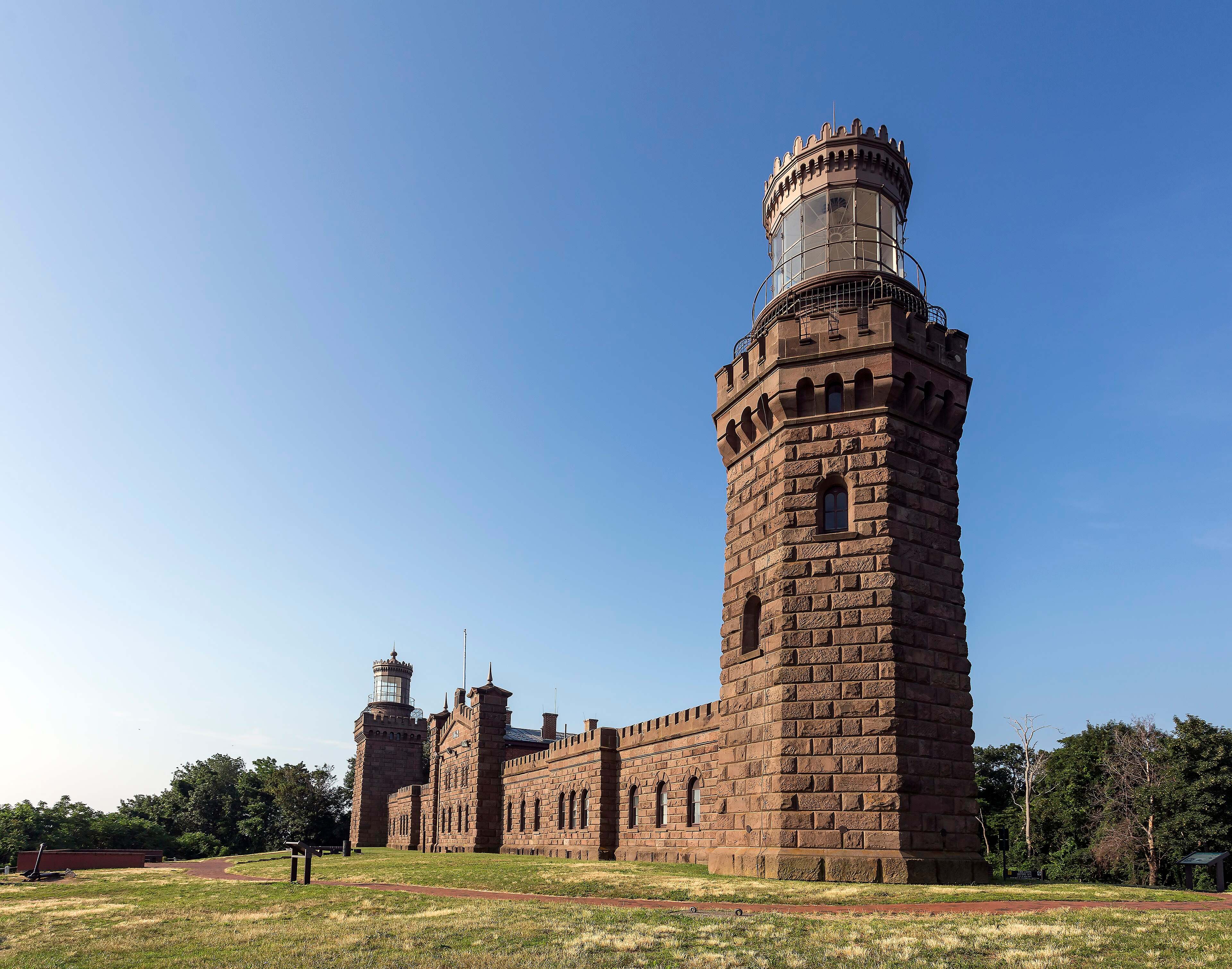 The north tower and brownstone fortress-style buildings of Twin Lights in Highlands under a clear blue sky.